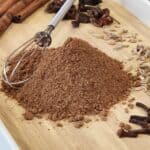 A stack of Chinese five spice powder on a tray with a small whisk.
