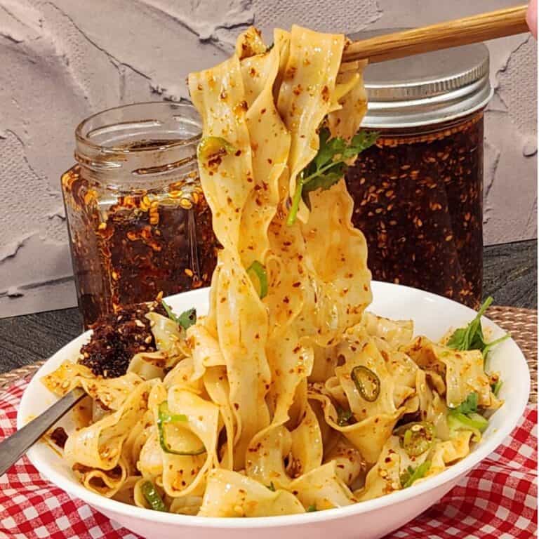 A pair of chopsticks holding garlic chili oil noodles.