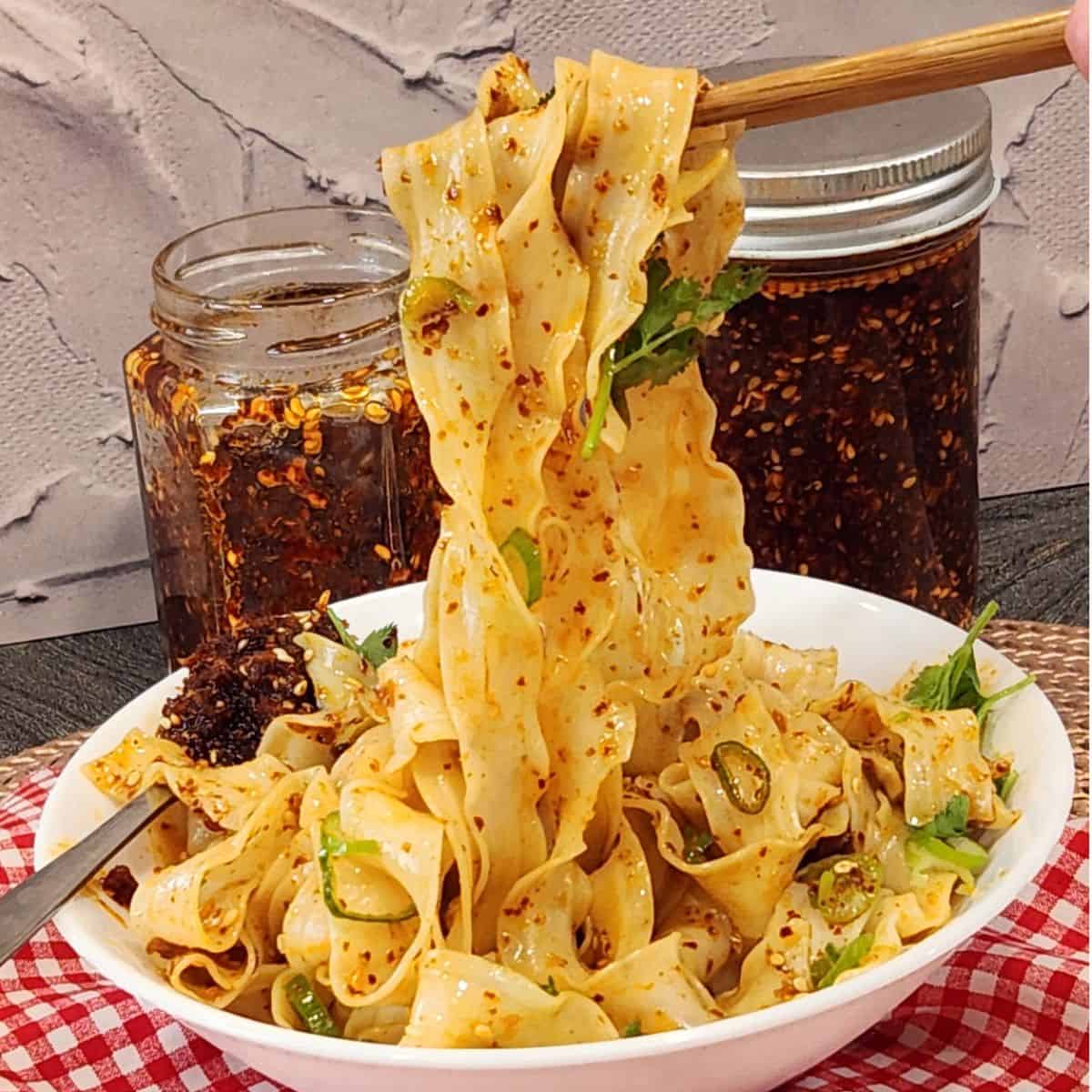 A pair of chopsticks holding garlic chili oil noodles.