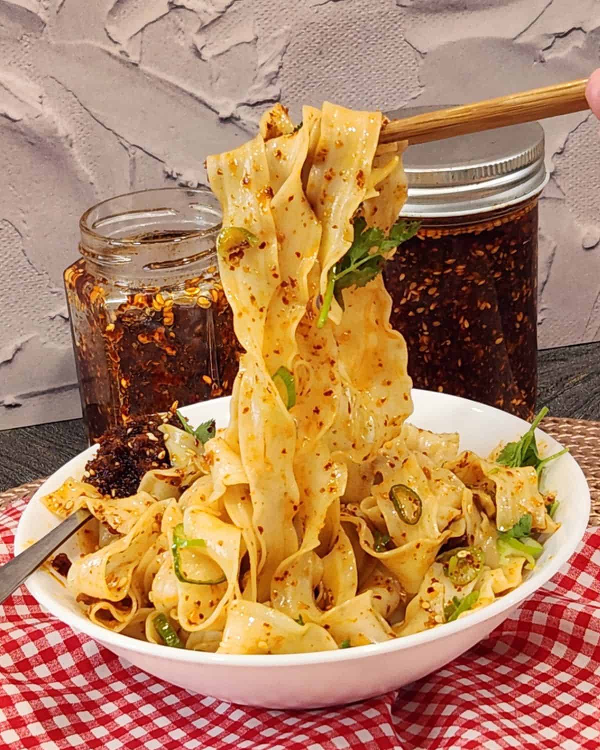 A pair of chopsticks holding garlic chili oil noodles.