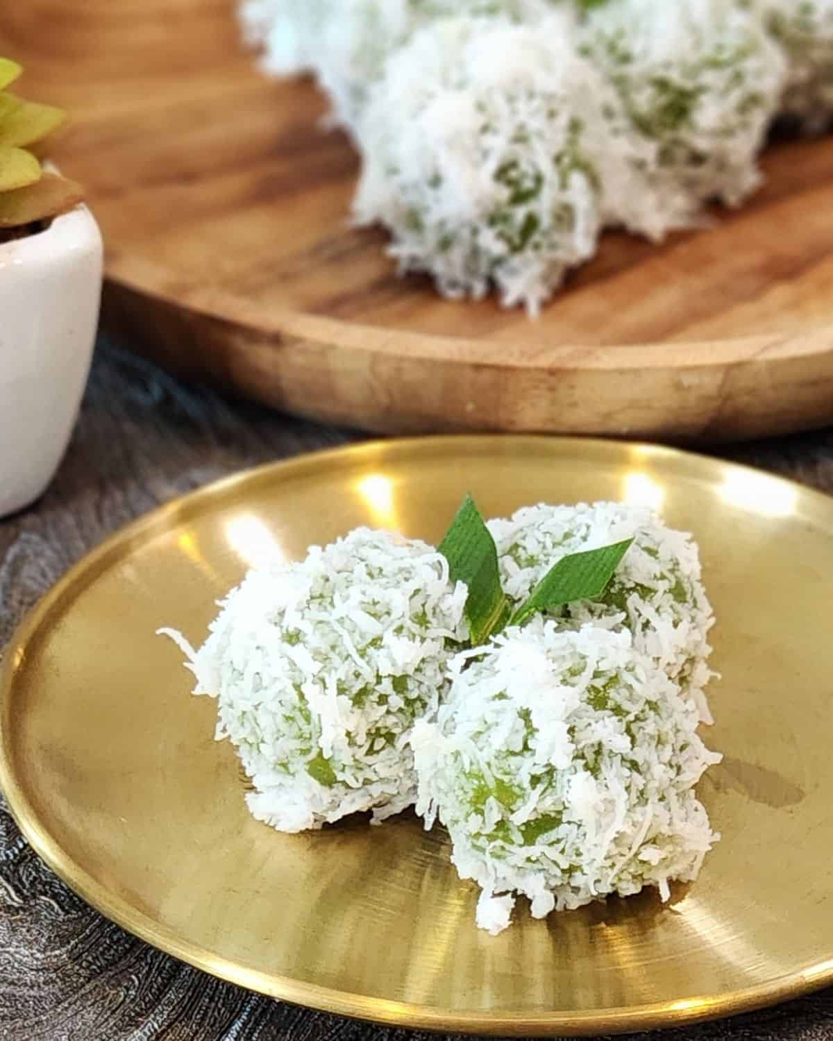 A golden plate with three ondeh ondeh or klepon.