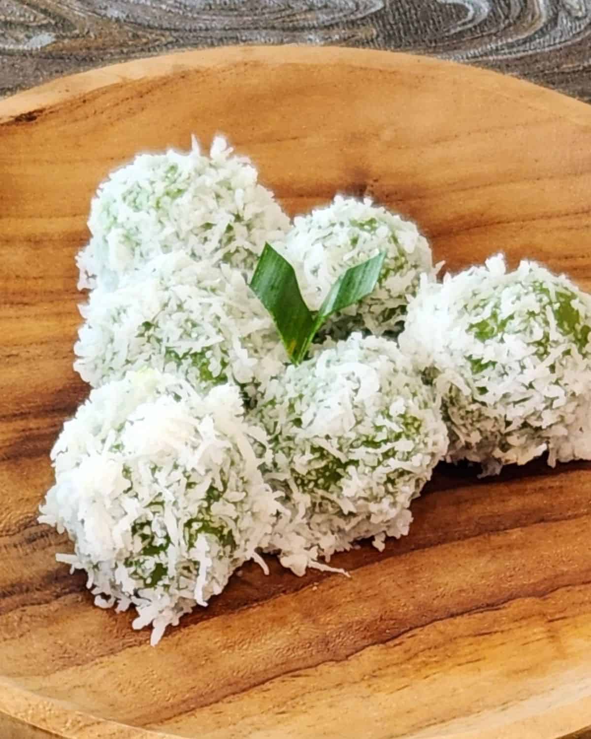 A small golden plate of three klepon or ondeh ondeh.