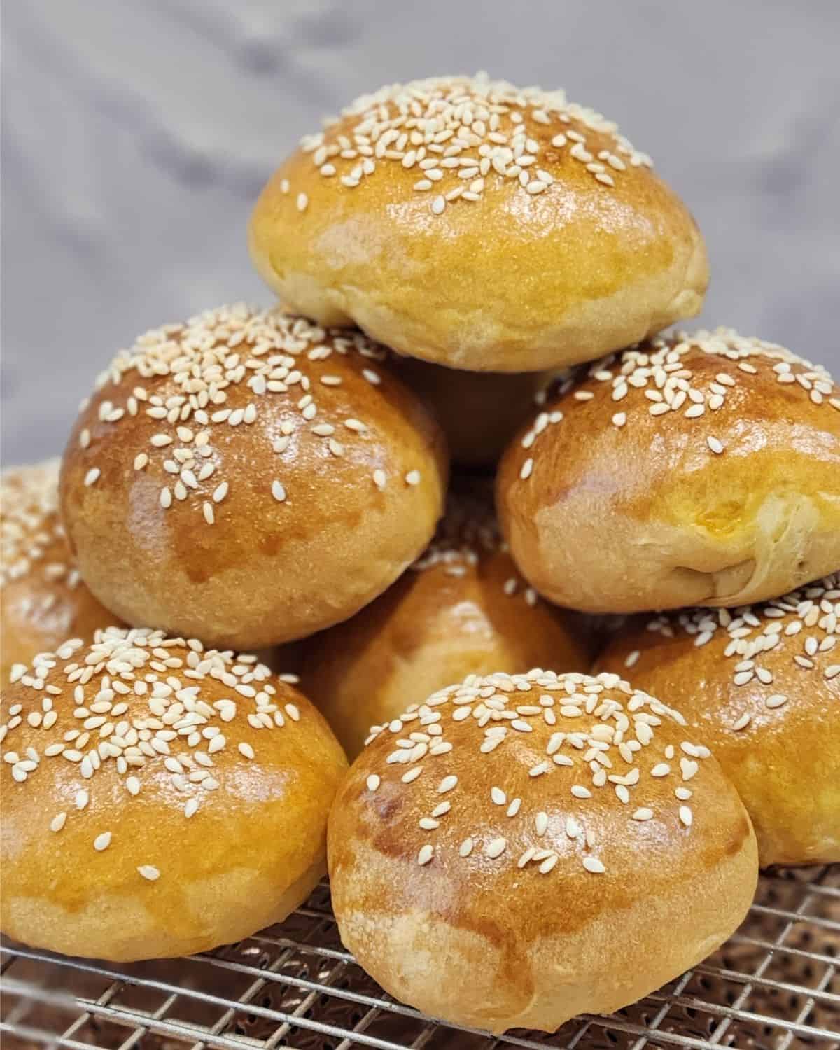 A stack of mini burger buns on a cooling rack.