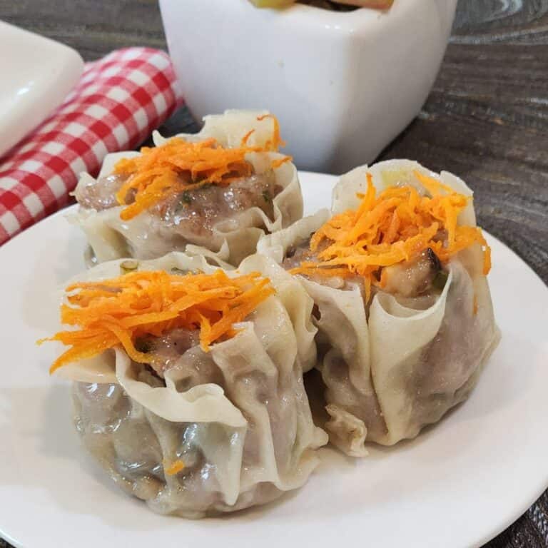 Three pieces of pork shao mai on a round plate.