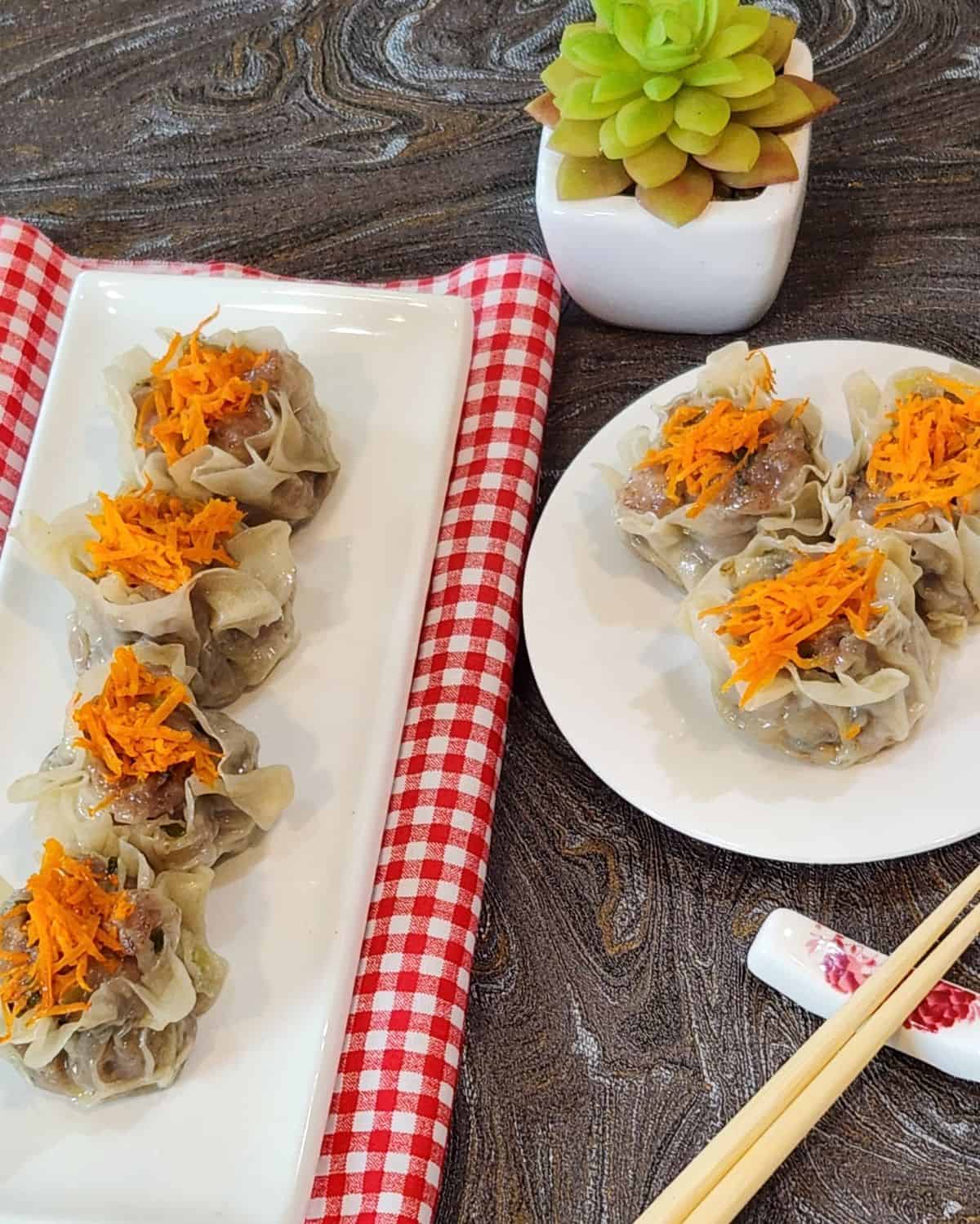 Two plates of pork shao mai with shrimp dumplings.
