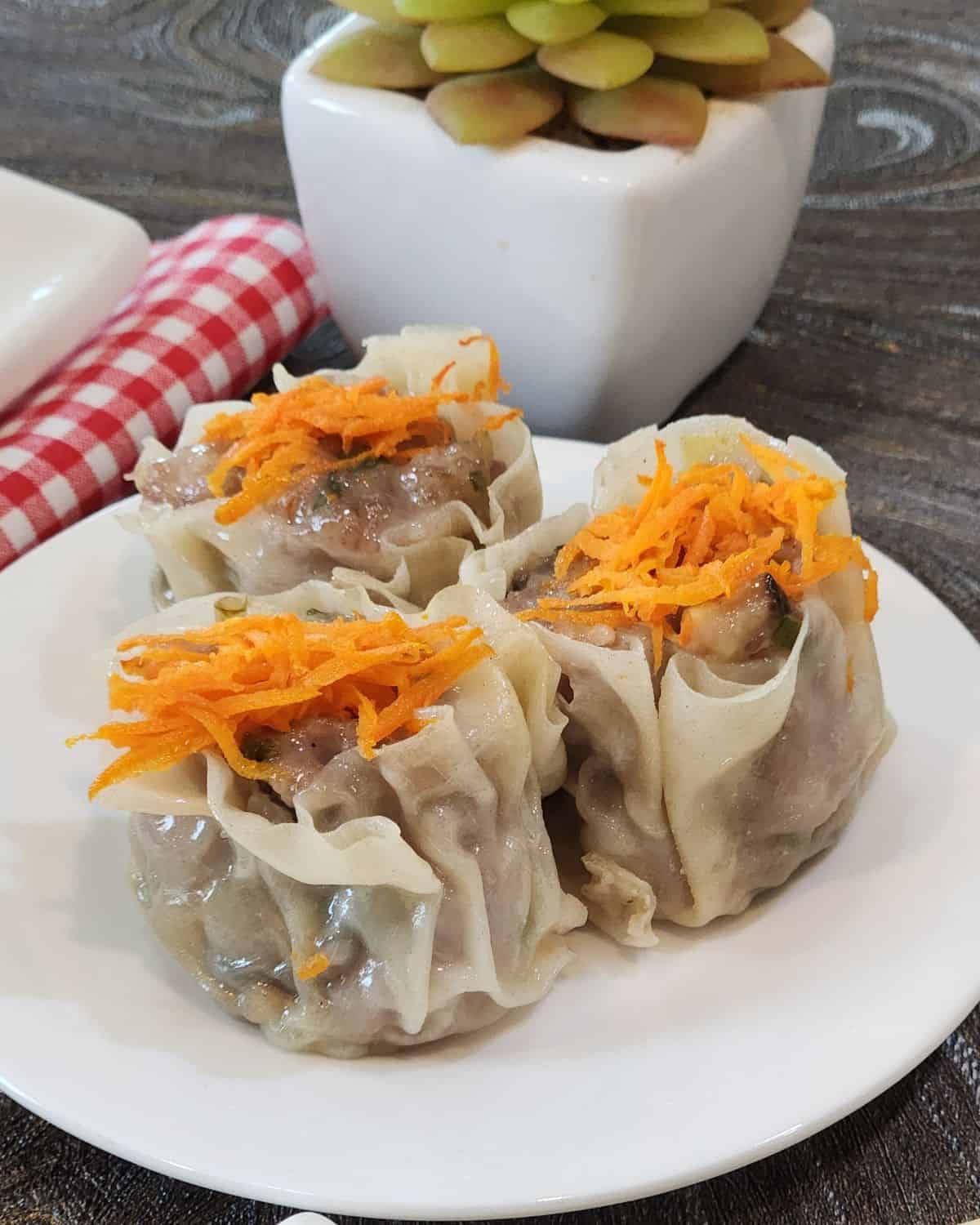 Three pieces of shao mai on a round plate.