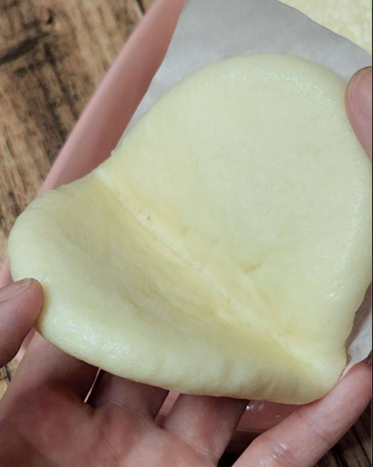 A hand holding an opened bao bun.