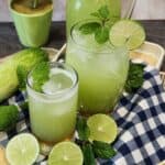 A glass of cucumber juice with mint, ice cubes, and lime.