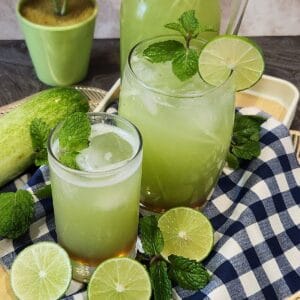 A glass of cucumber juice with mint, ice cubes, and lime.