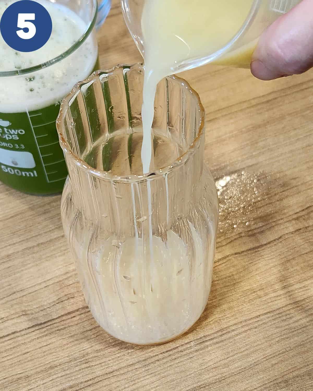 Pouring lime juice into a pitcher for cucumber juice drink.