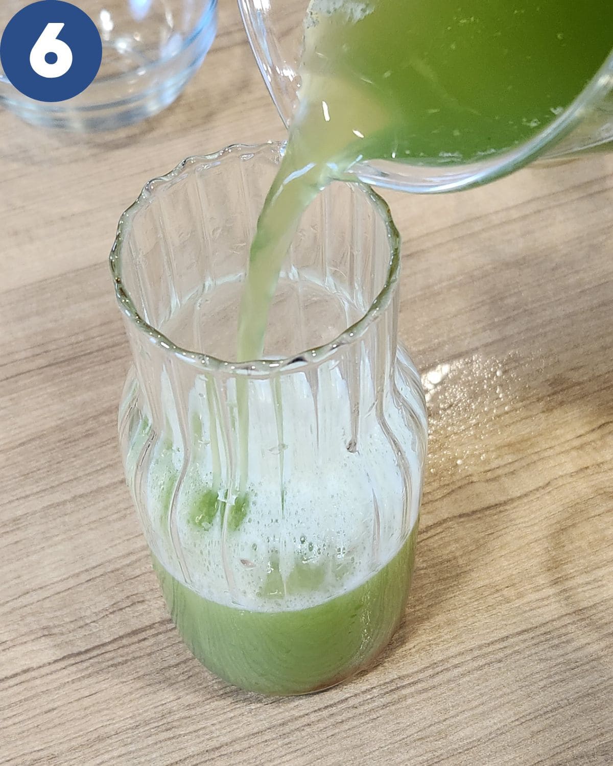 Pouring cucumber juice drink into a pitcher.