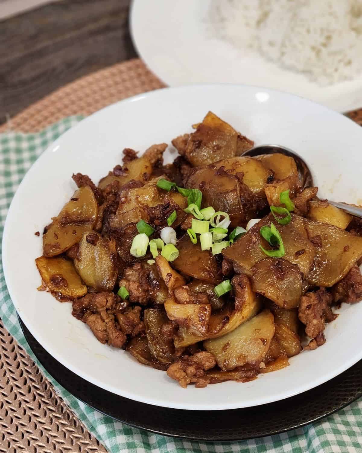 A plate of ground pork stir fry with potatoes, sprinkled with green onion.