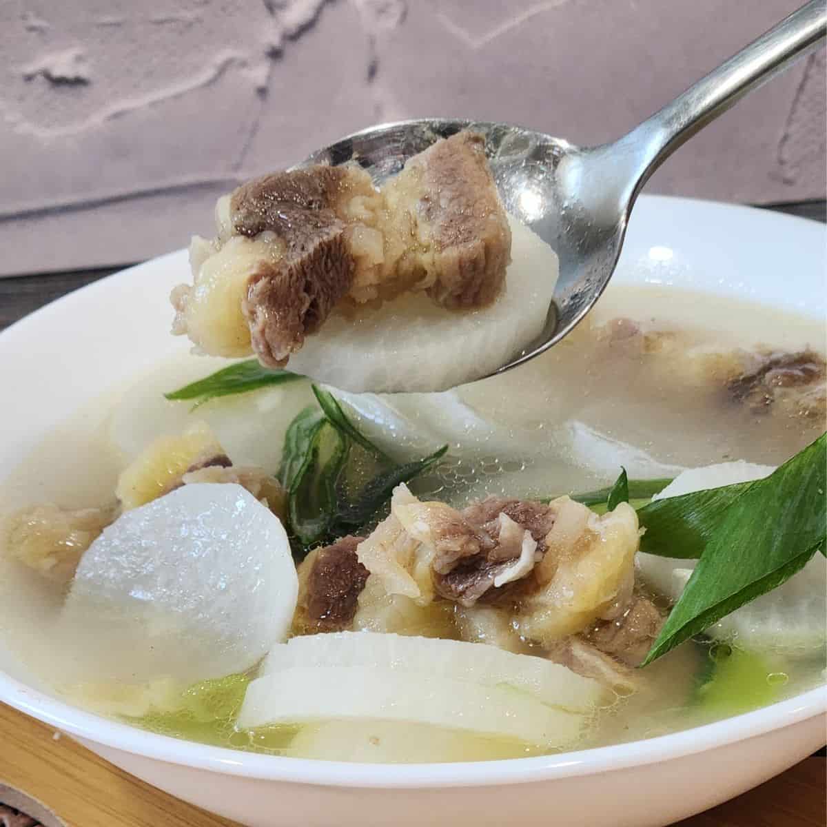 A spoon with Korean beef soup with radish (Soegogi Muguk).