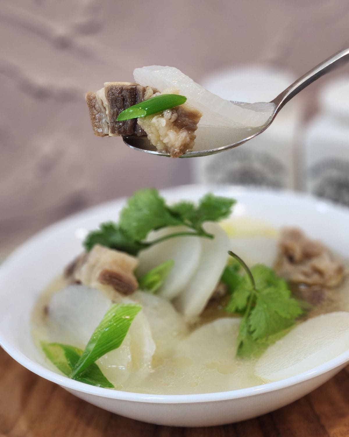 A spoon holding Korean beef soup with radish.