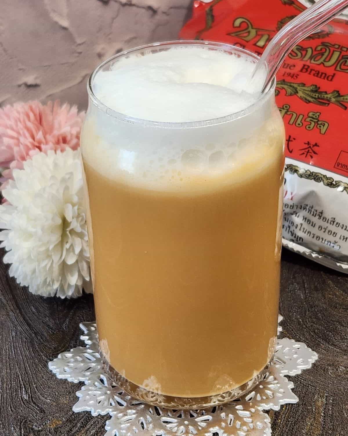 Thai Tea with frothed milk on top and chatramue package at the back.
