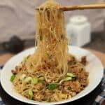 A pair of chopsticks holding ants climbing a tree glass noodles.