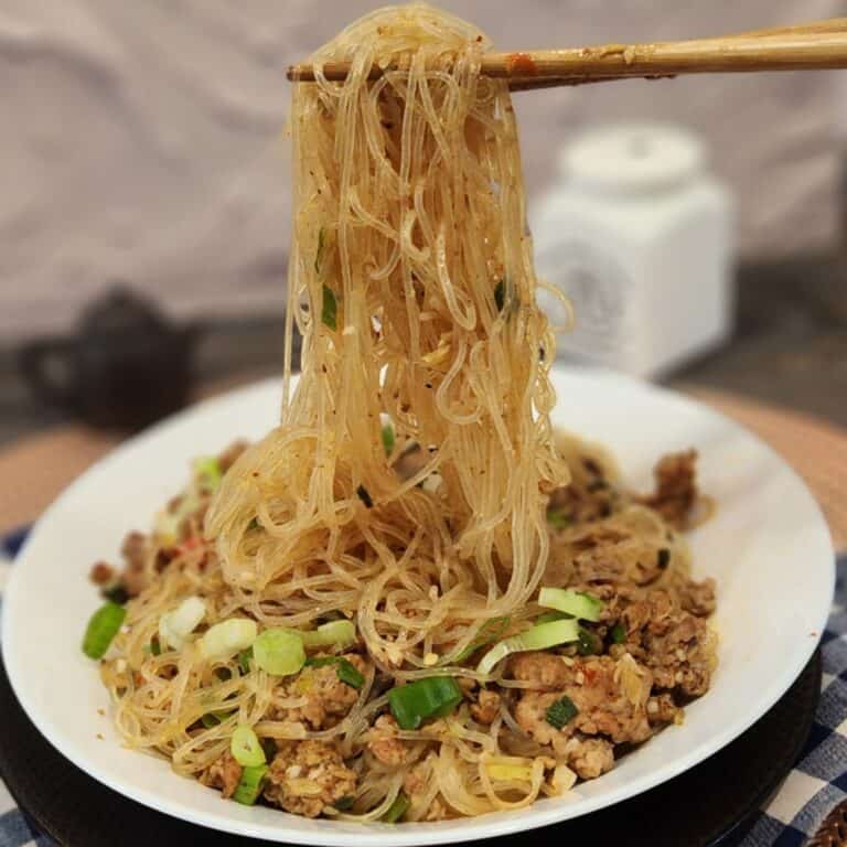 A pair of chopsticks holding ants climbing a tree glass noodles.