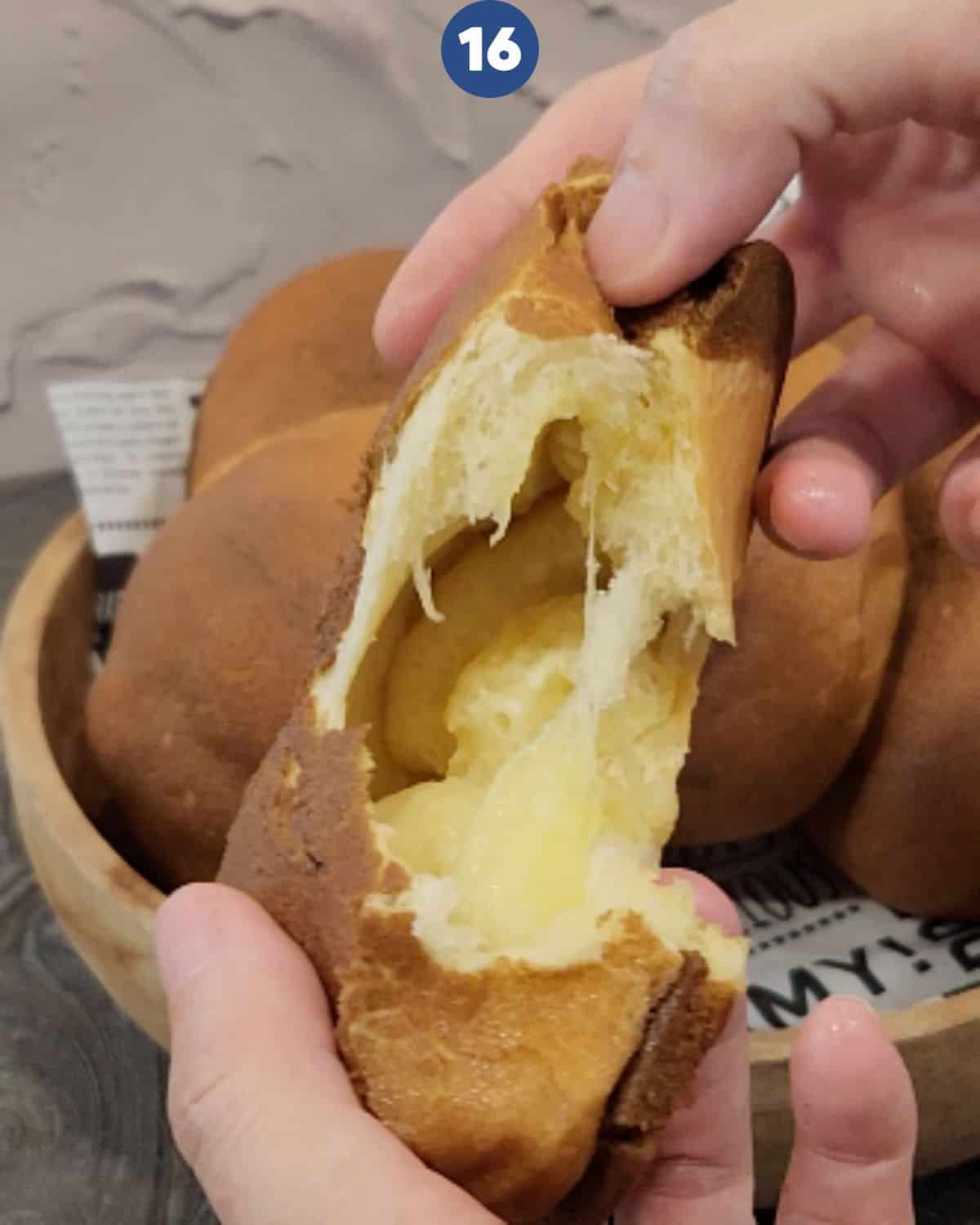 A piece of coffee bun being torn to show the melted butter inside.