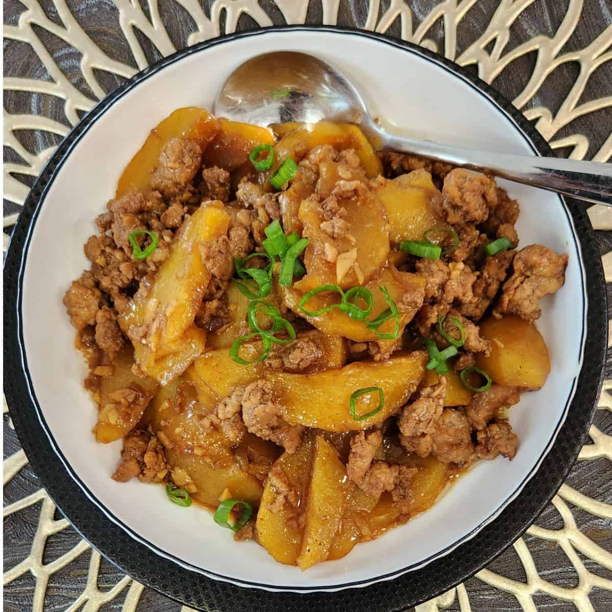 A plate of ground pork stir fry, garnished with green onion.