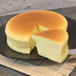 A slice of Japanese cheesecake after being cut in front of the whole loaf.