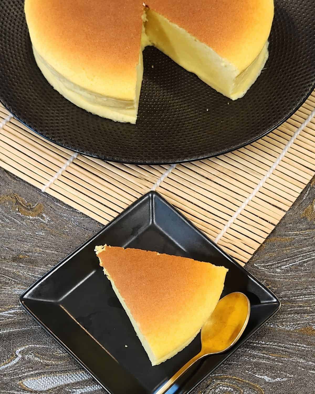 A slice of Japanese cheesecake on a black plate.