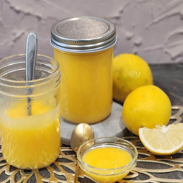 Two jars of lemon curd with lemon at the background.