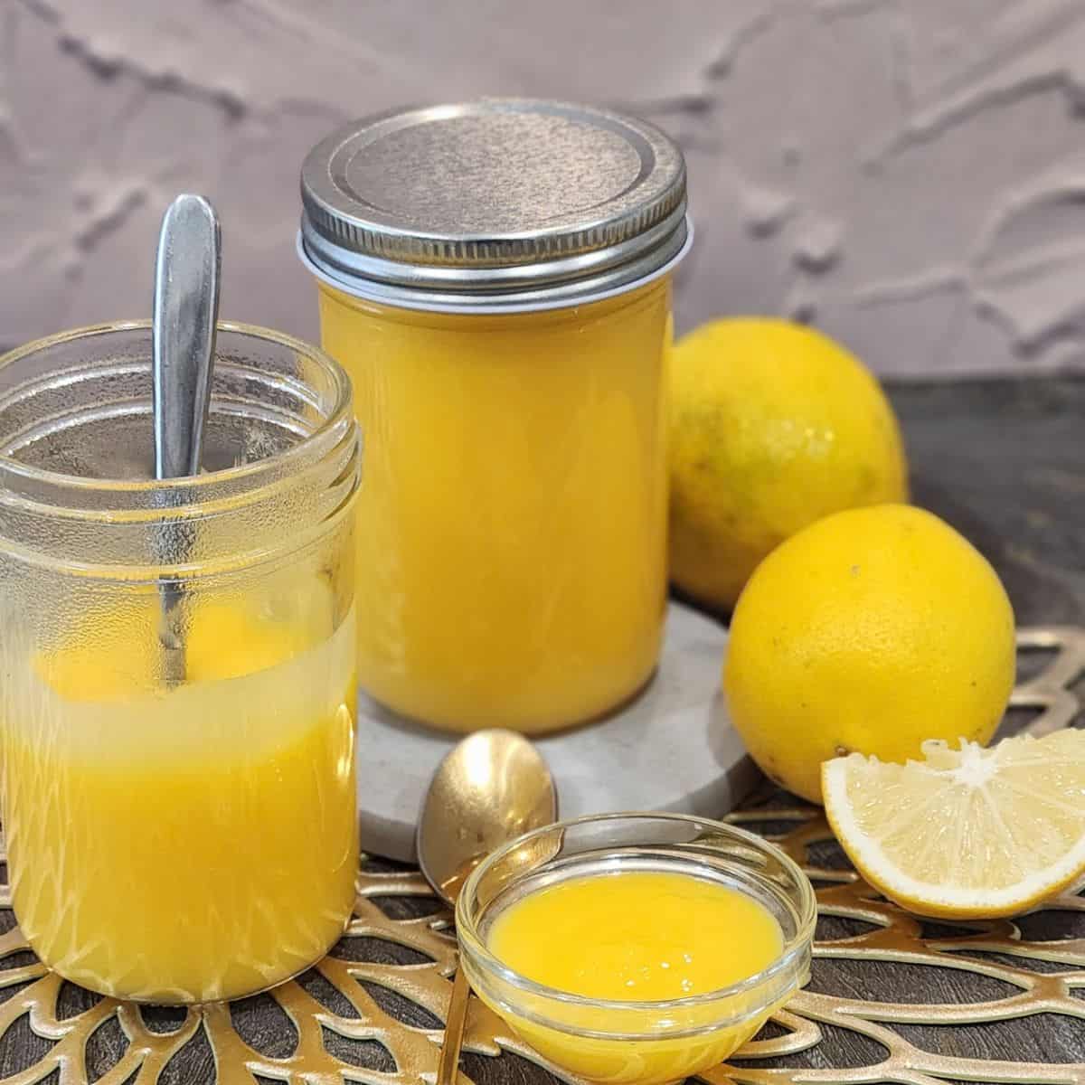 Two jars of lemon curd with lemon at the background.