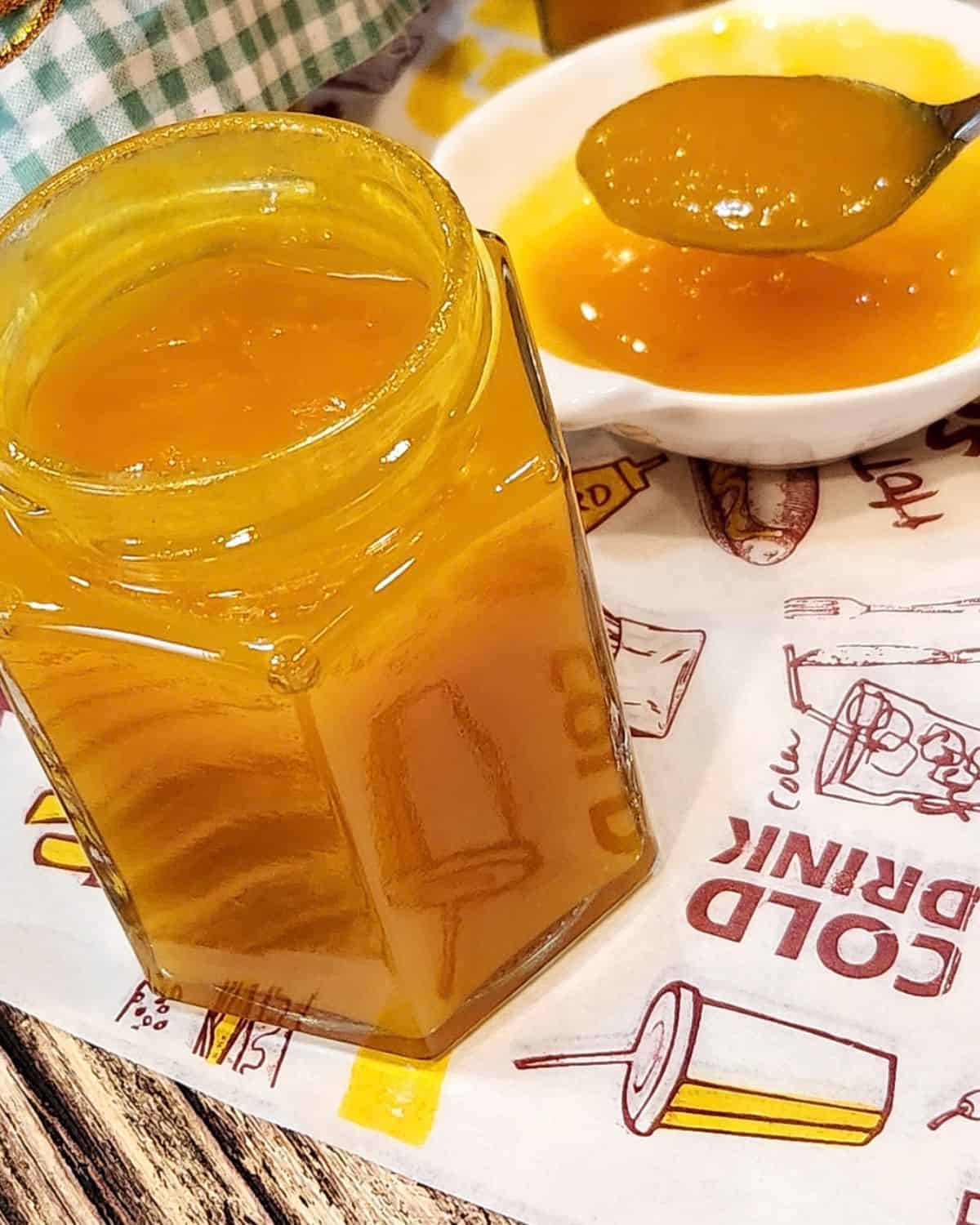 An open jar of mango jam with a small plate next to it.