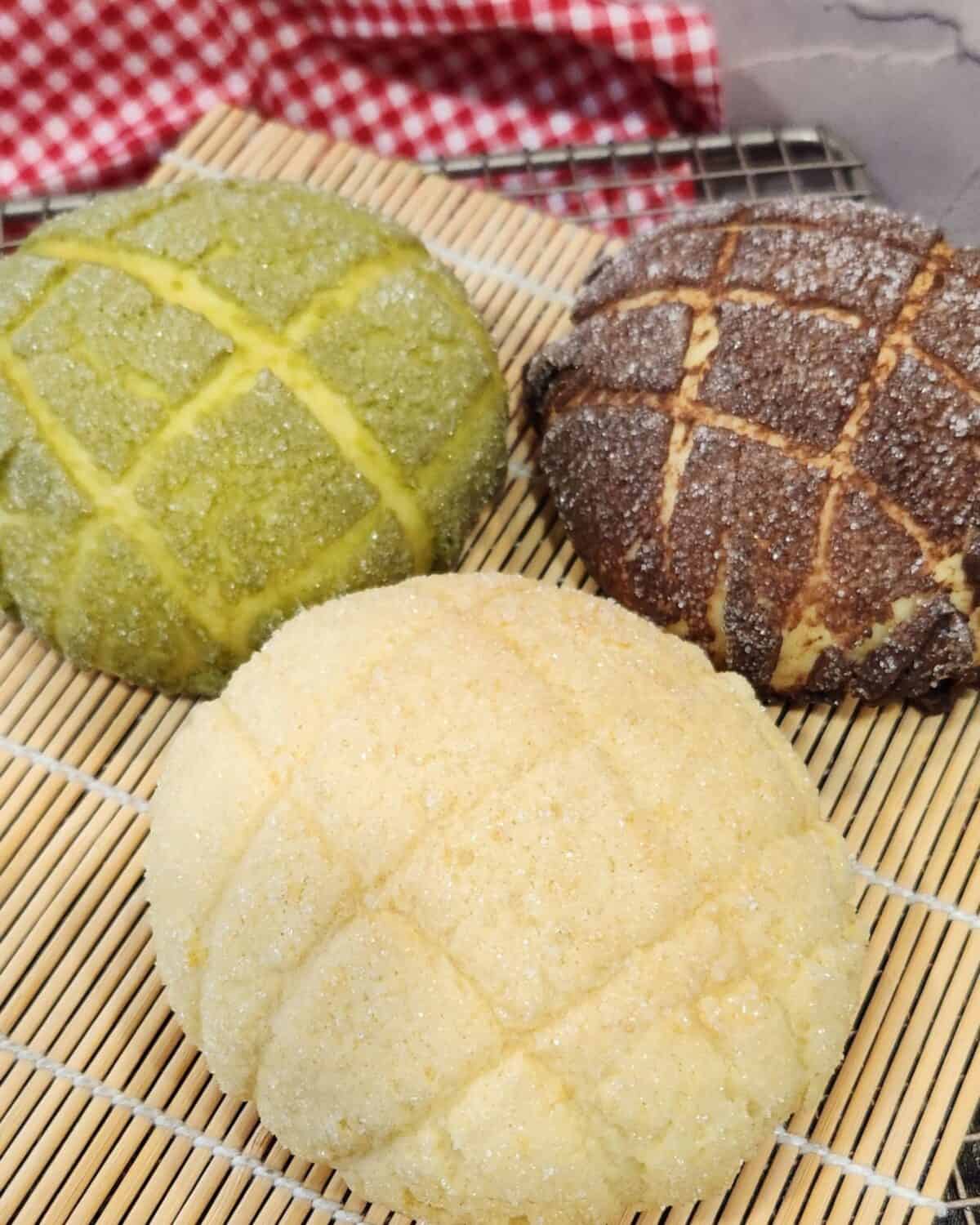 Three flavors of melon pan on a bamboo tray.