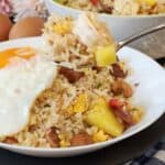 A plate of pineapple shrimp fried rice with fried egg on top.