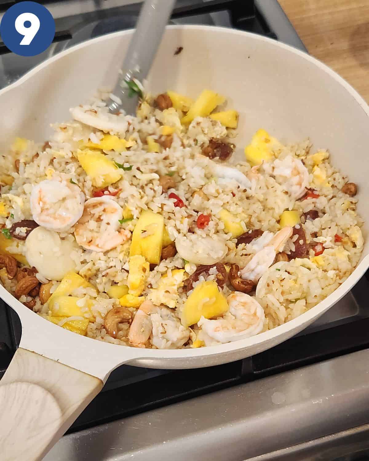 Stirring pineapple fried rice in the wok.