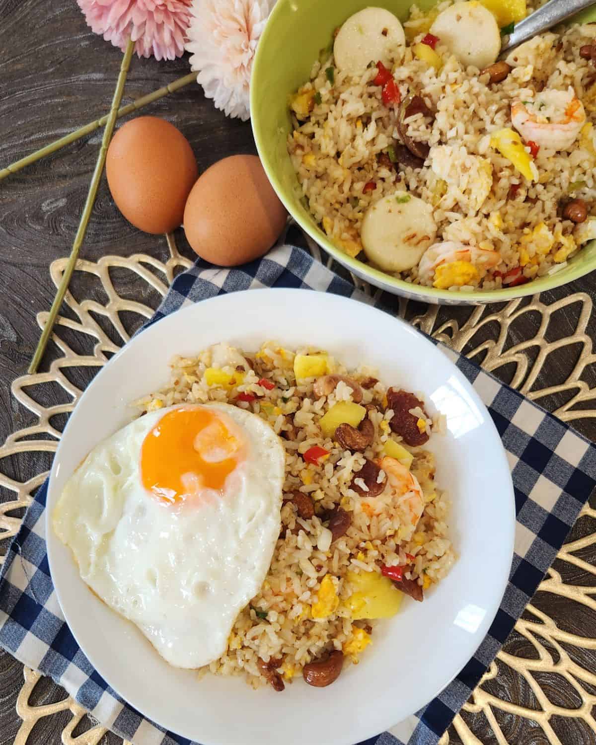 A plate of pineapple shrimp fried rice with fried egg on top.