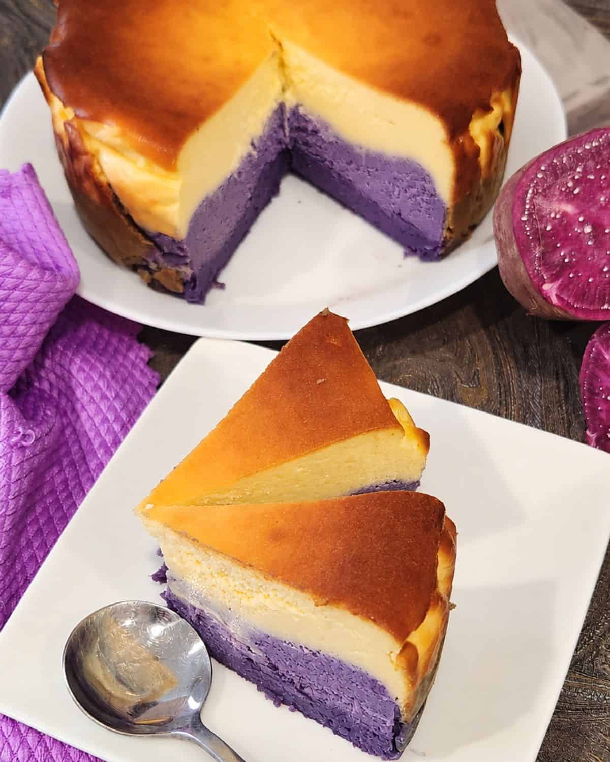 Two slices of ube cheesecake on a square plate with a loaf at the back.