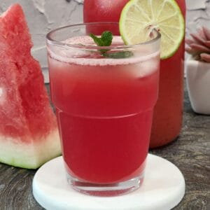 A glass of watermelon juice with pineapple, lime, and mint.