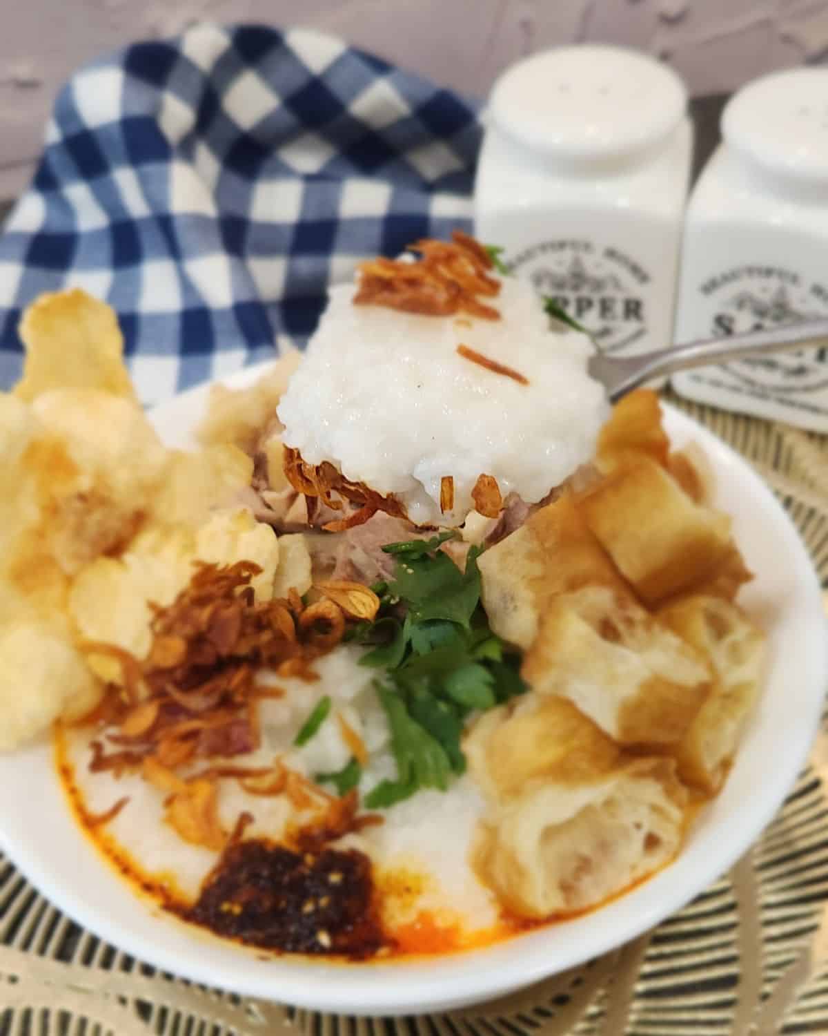 A spoon holding chicken congee showing the creamy texture. 