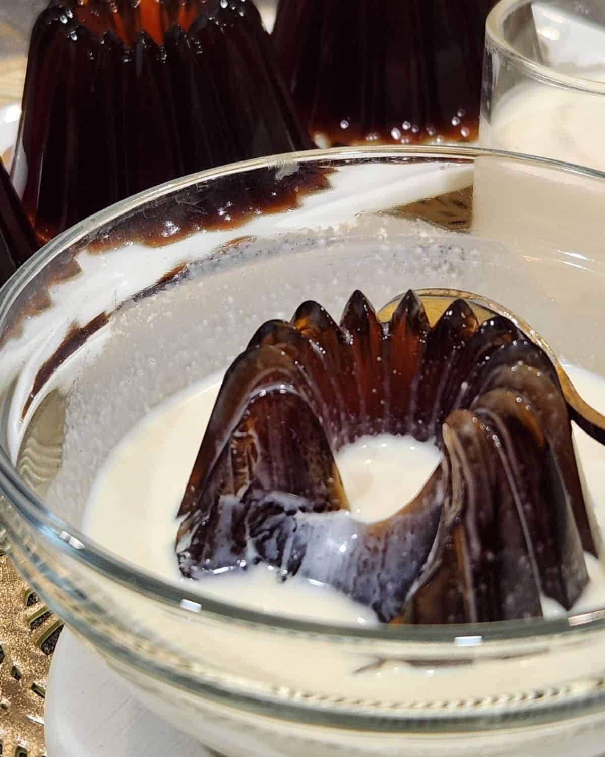 A bowl with coffee jelly dessert and milk sauce.