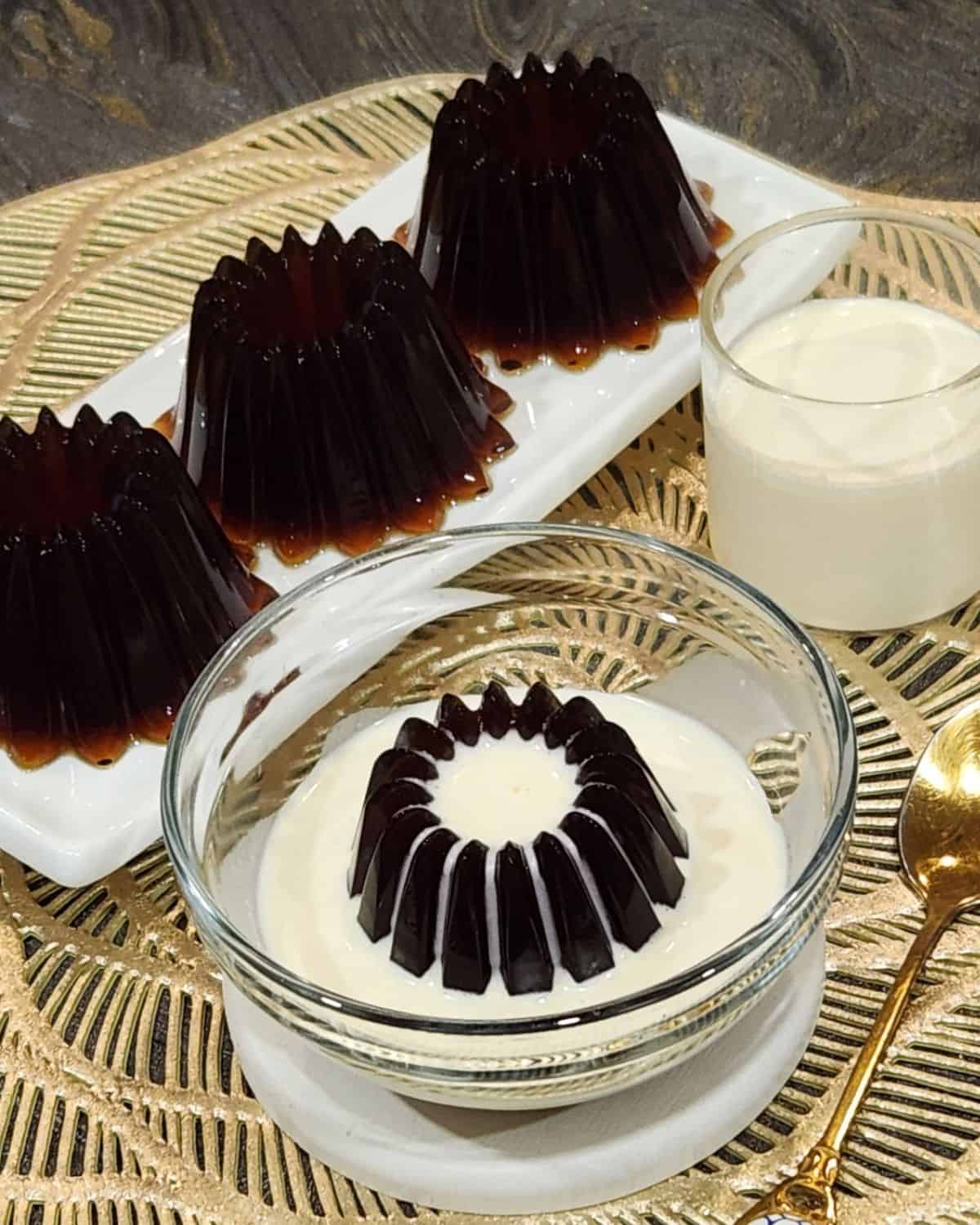 A few Japanese coffee jelly dessert on a long white plate with creamy sauce.