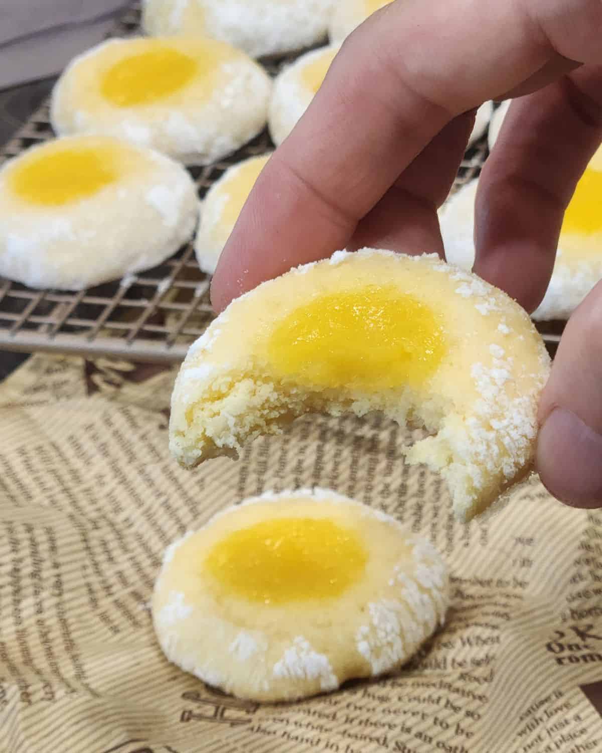 A hand holding half-bitten lemon curd cookies.