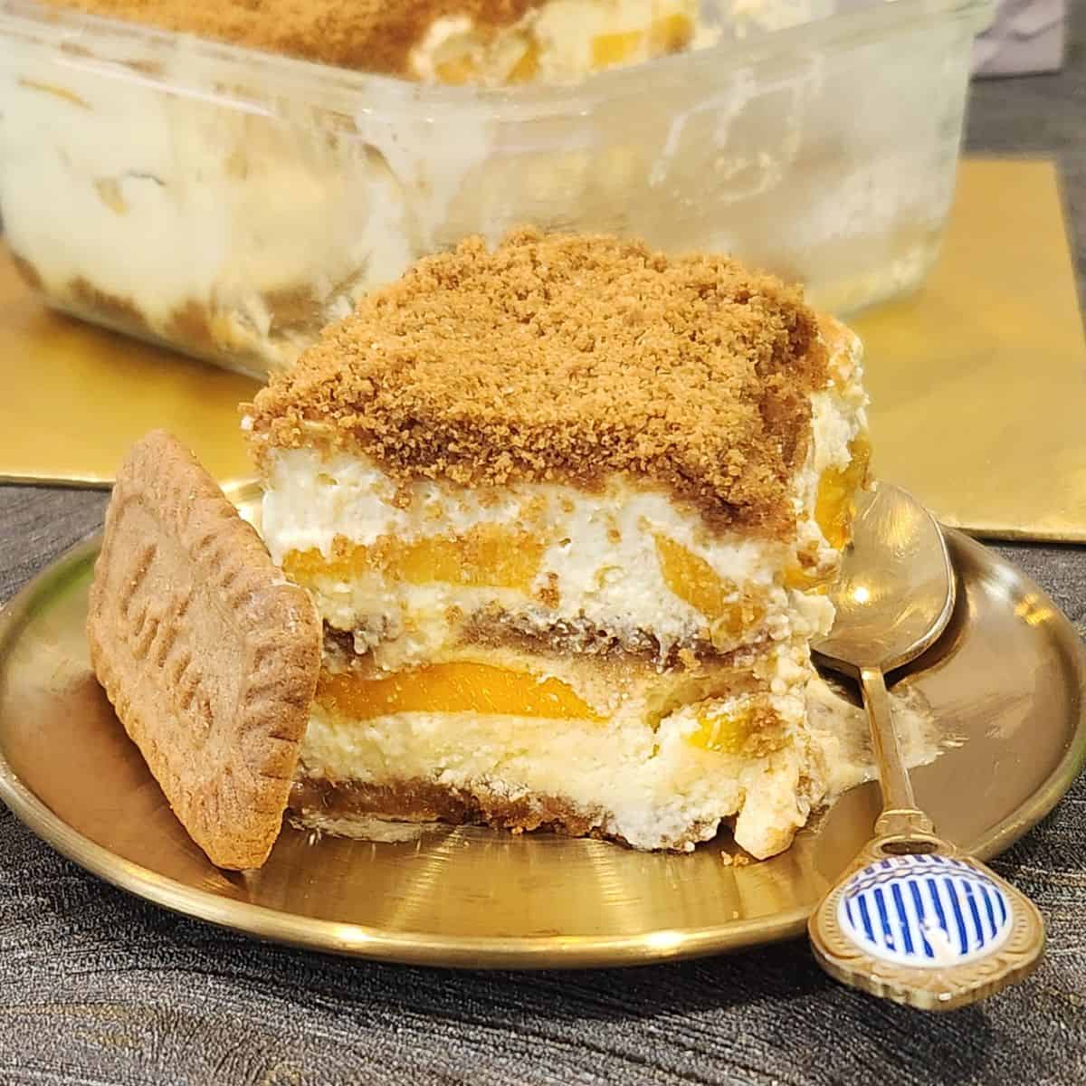A piece of mango float with lotus biscoff on a golden plate.