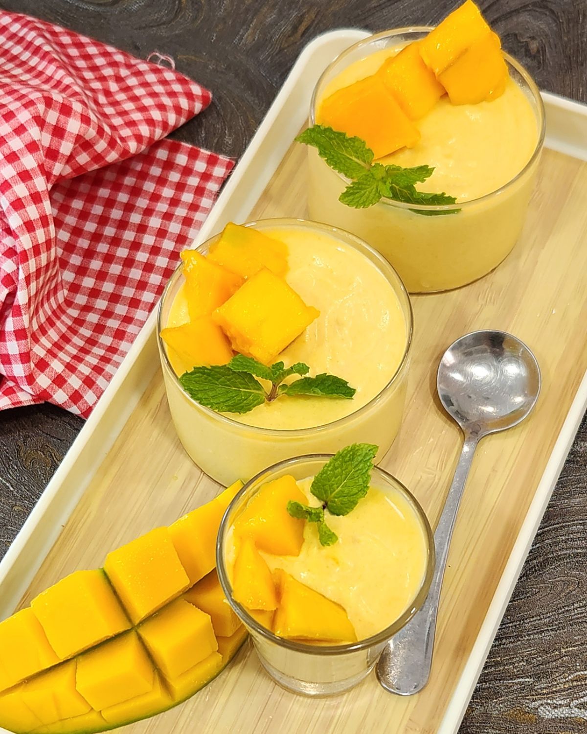 Three glasses of mango mousse on a tray.
