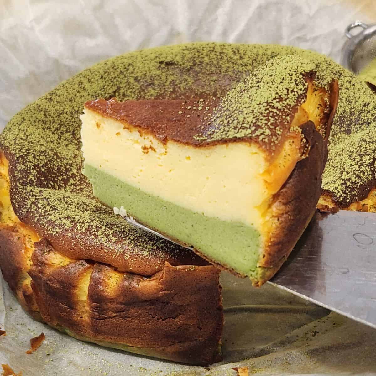 A spatula holding a slice of matcha cheesecake.