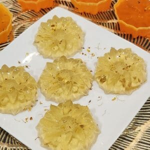 Five Osmanthus jelly on a plate with some osmanthus flowers sprinkled on it.