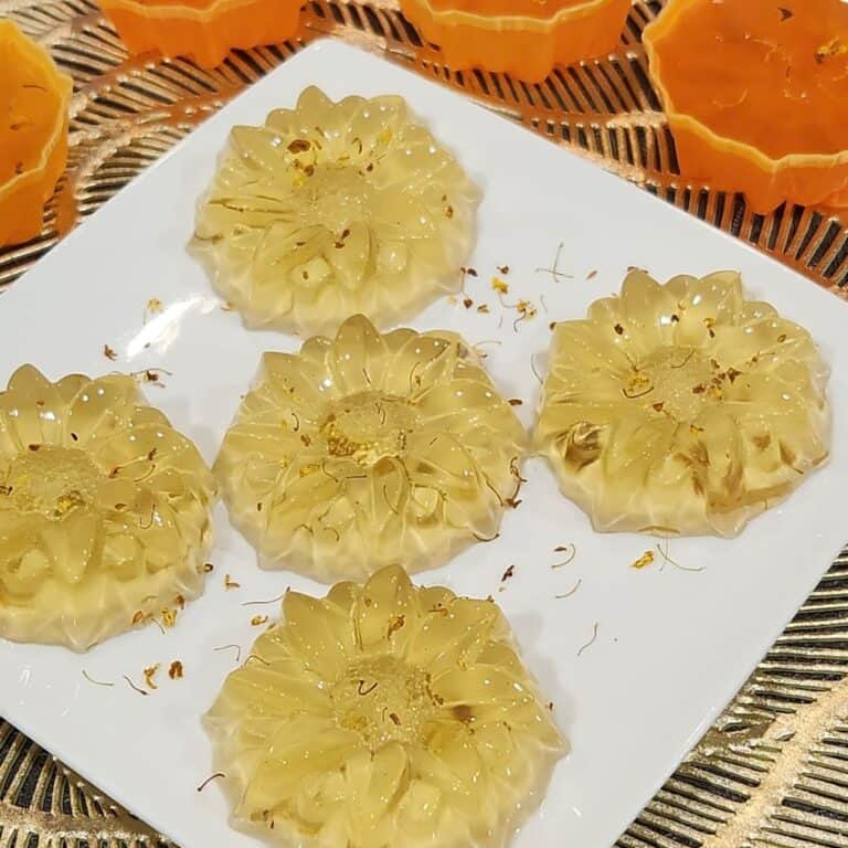 Five Osmanthus jelly on a plate with some osmanthus flowers sprinkled on it.
