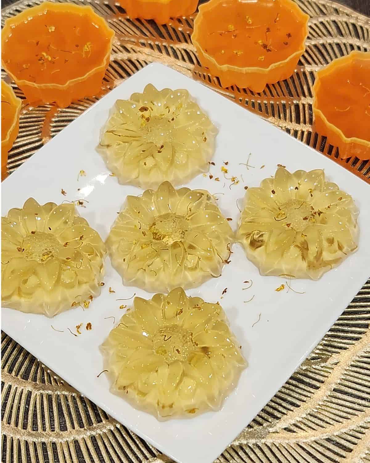 Five Osmanthus jelly on a plate with some osmanthus flowers sprinkled on it.