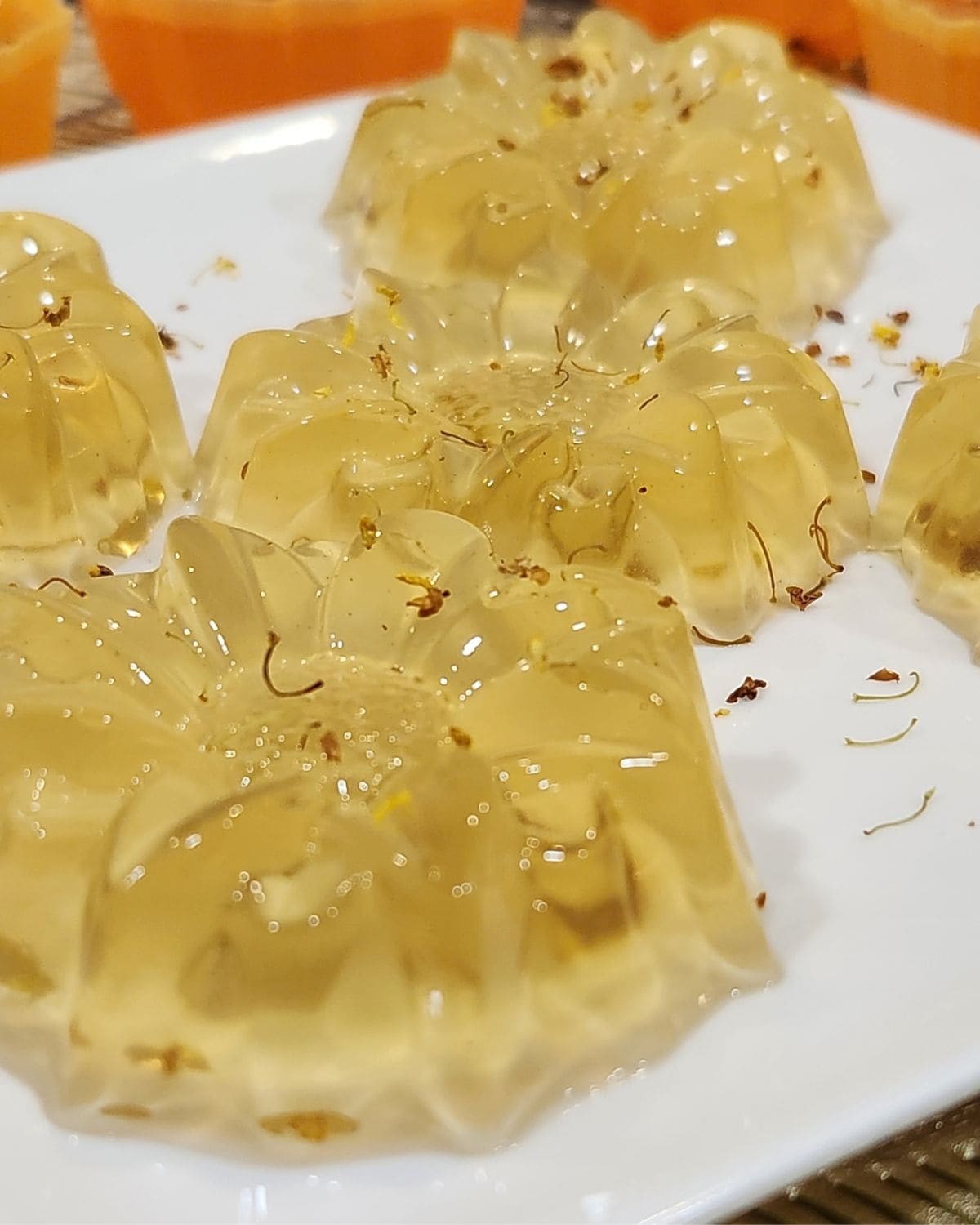 Osmanthus jelly on a white plate with some flowers.