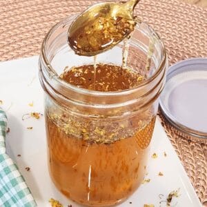 A golden spoon with drizzling osmanthus syrup on top of a jar.