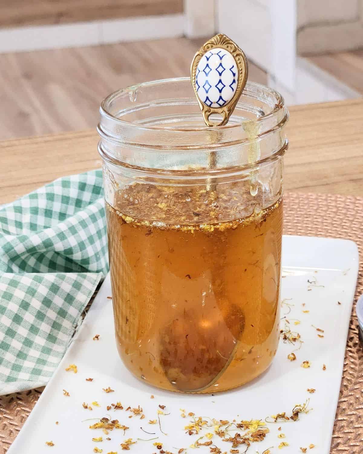 A jar of osmanthus syrup with a golden spoon in it. 