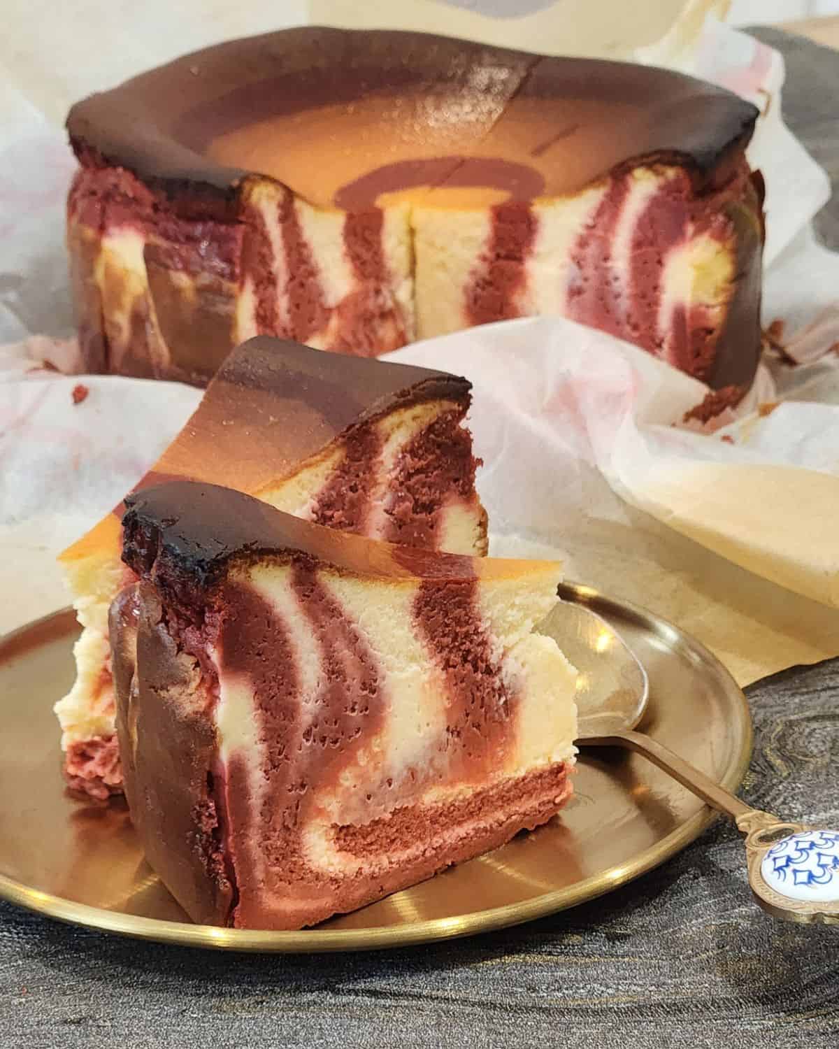 Two slices of red velvet cheesecake on a golden plate. 
